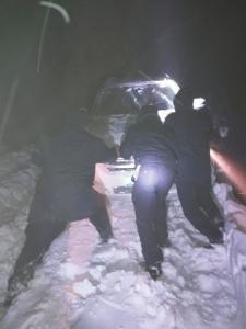 車(chē)陷雪中，民警徒手扒雪推車(chē)。