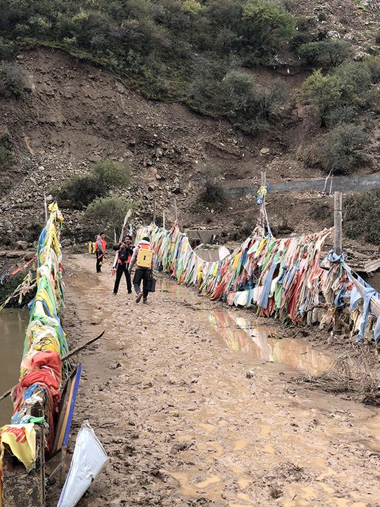 監測人員踩著泥濘道路轉移觀測點。昌都市水文局圖