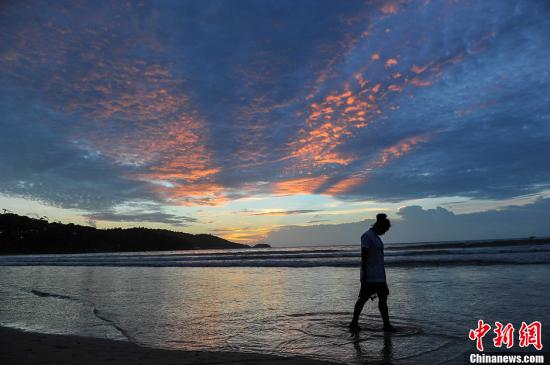 泰國普吉島，圖為一名游客從海灘上走過。洪堅鵬 攝