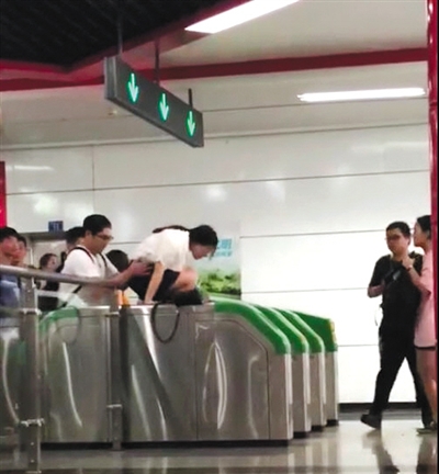 爬 一女子在男同伴的“扶助”下，爬過地鐵檢票閘機(jī)口。視頻截圖