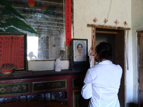 李春蘭望著母親的遺像喃喃自語，最終掩面哭泣。