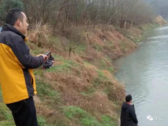 身著沖鋒衣的梁峰關心地看著水面上救援工作的進行