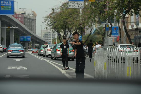 3月17日下午，廣州市白云世界皮具貿易中心門前的解放北路，一名拉客人員在機動車道上往一輛私家車內遞名片。 新京報記者 吳江 攝