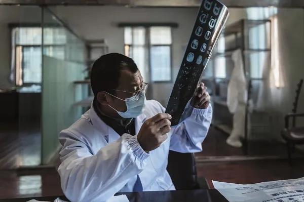 3月7日，硚口區(qū)六角亭街道社區(qū)衛(wèi)生服務(wù)中心主任羅浩在一間臨時的辦公場所對著窗戶看CT片。